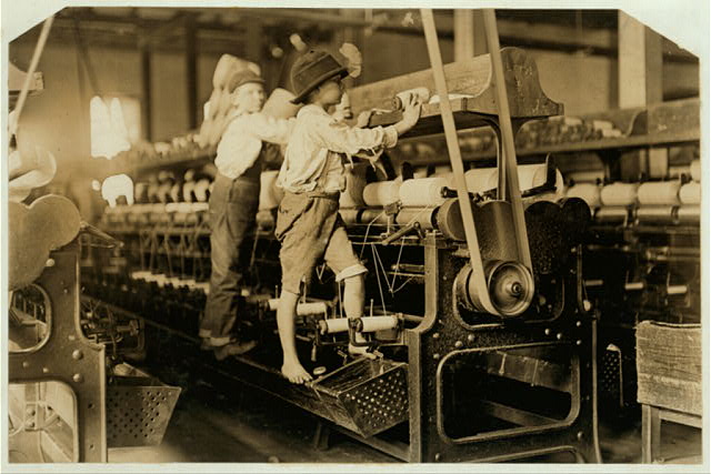 Two young boys working barefoot on spinning machinery at Bibb Mill in 1909