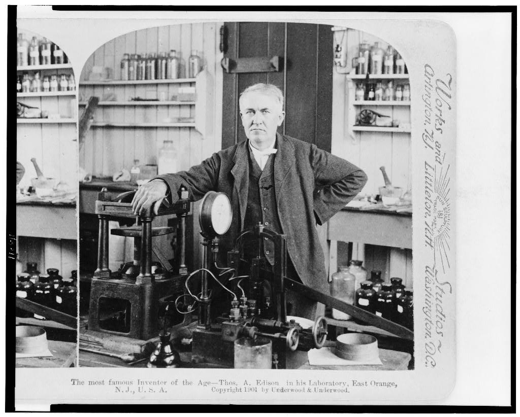 Thomas Edison standing with equipment inside his laboratory around 1901